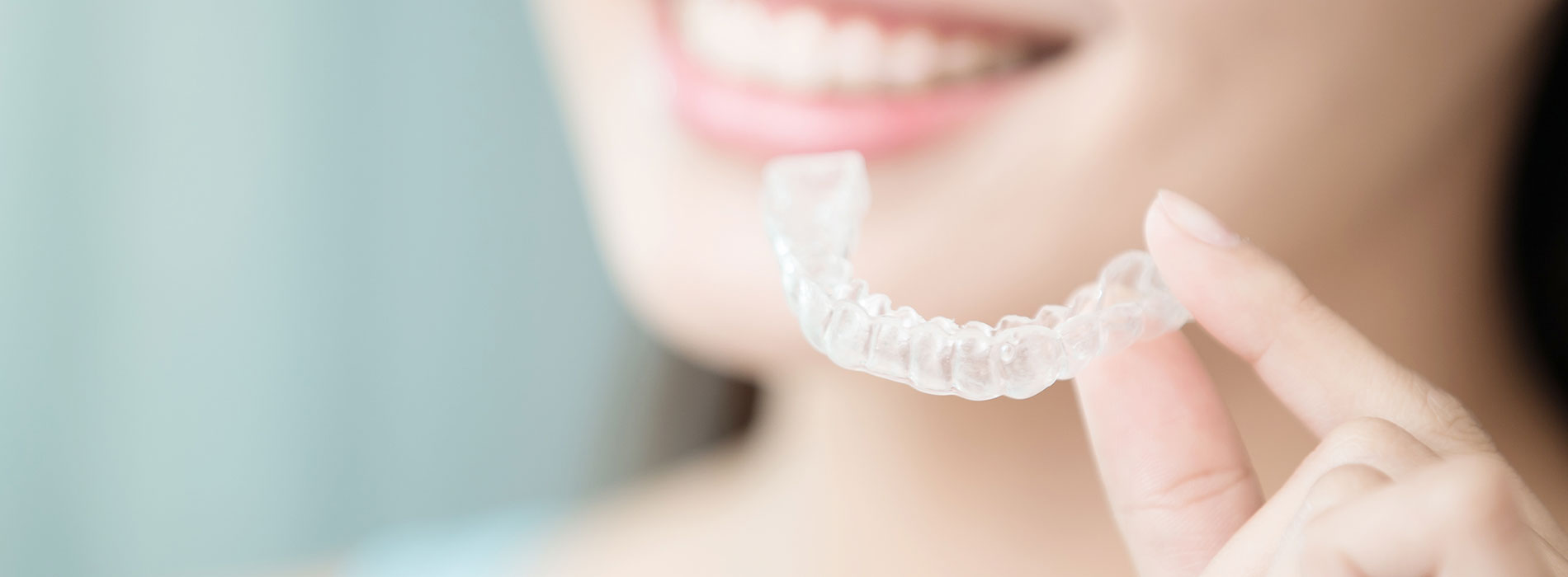 A person holding a transparent mouth guard with their right hand.