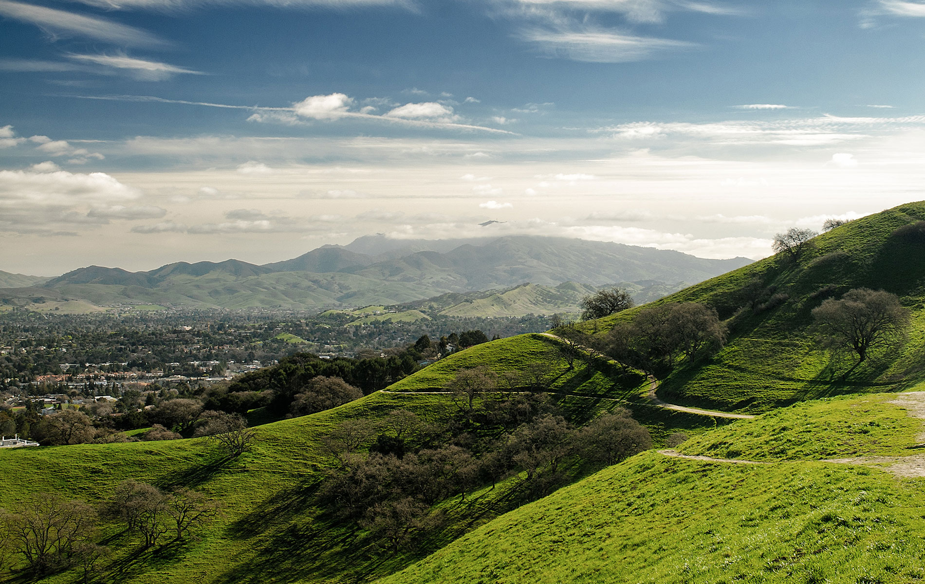 The image shows a picturesque landscape with lush green hills and a clear blue sky above.