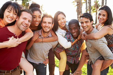 A group of smiling people posing together outdoors during daylight.